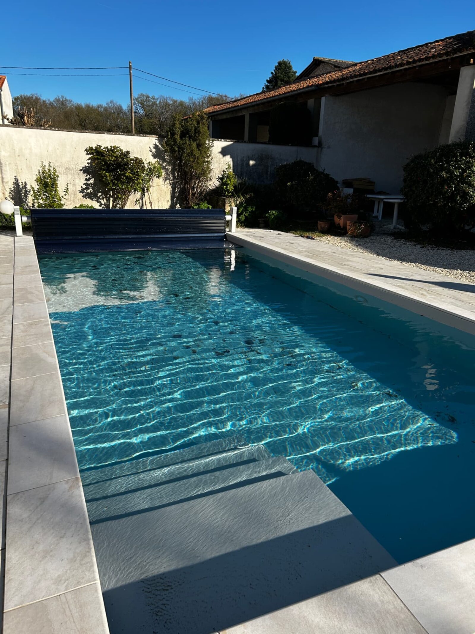 Piscine rénovée avec volet automatique et margelles claires